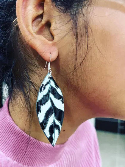 A student wearing the beautiful leaf-patterned enamel earrings she created from scratch in our two-day workshop.