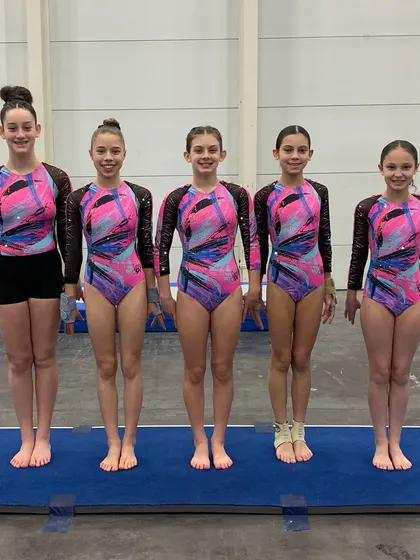 A group of our Xcel athletes posing on the floor before their session at the invitational.