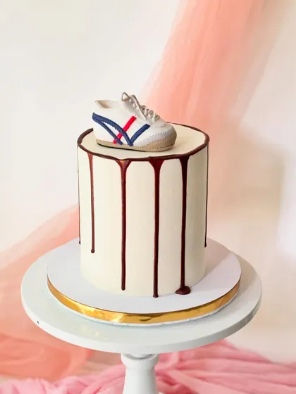 A minimalist cake for a sneakerhead, topped with a hand-sculpted, realistic Onitsuka Tiger shoe. The clean design is finished with a simple chocolate drip.