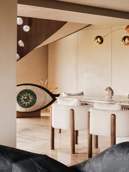 A glimpse of the dining area from the living room, with the eye-shaped sculpture in the background. This composition highlights the open, flowing nature of the space and its art-filled corners.