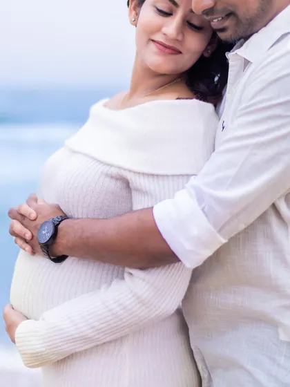 A detailed shot focusing on the loving embrace around the baby bump, a simple yet powerful image of protection and love.