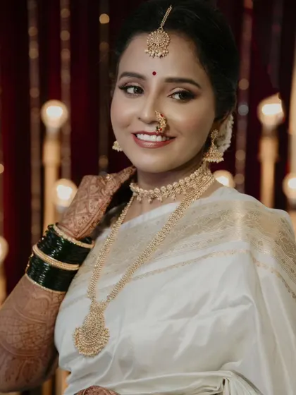 A radiant bridal portrait. The bride's happy smile and the warm, glowing lights in the background create a photograph that is full of joy and celebration.