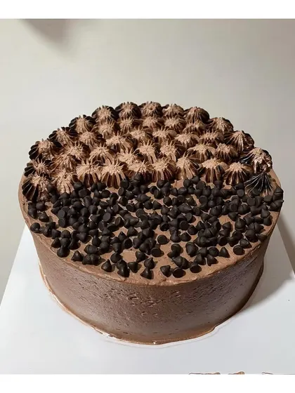 A half-and-half Dutch truffle cake design, with one side covered in choco chips and the other with piped cream.