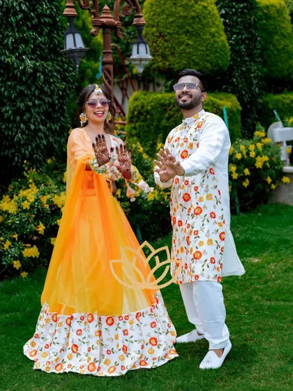 A happy couple showing off their matching mehendi designs during their outdoor photoshoot. The stain looks vibrant and beautiful.