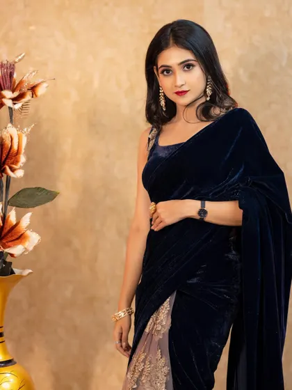 A three-quarter portrait that shows off the beautiful design of the velvet saree. The subject's direct gaze adds a touch of confidence and allure.