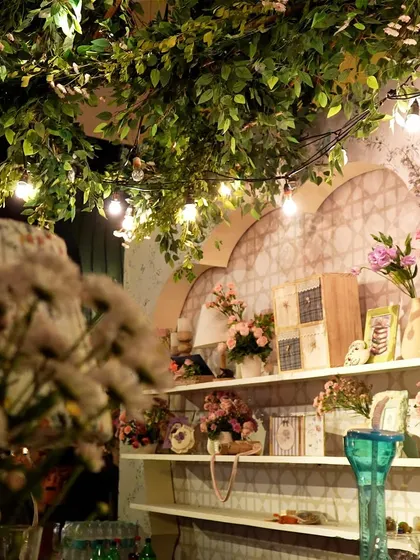 A shelf of decor details illuminated by string lights, with foliage creating a natural canopy.