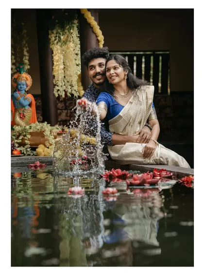 A joyful shot of a couple creating a splash in a pond filled with flowers.