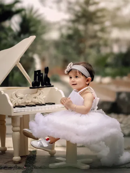 A little angel at the piano. Dressed in a fluffy white dress, she looks absolutely ethereal while playing her tune in a lovely garden setting.