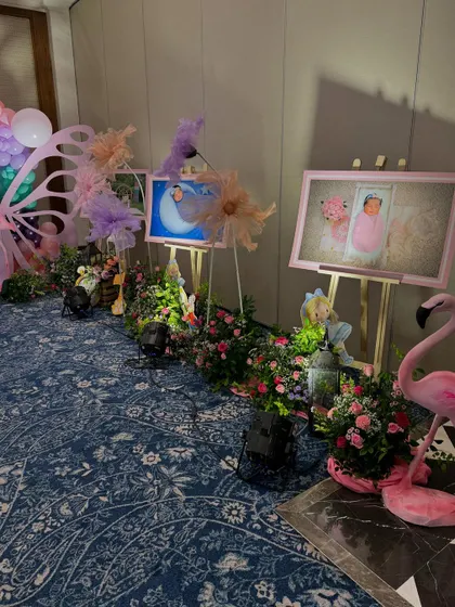 A walkway decorated with lush flower arrangements and framed photos of the birthday girl, creating a personal and enchanting path for guests.