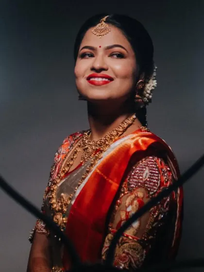 A dramatic portrait of the bride in her off-white and orange saree, her smile lighting up the frame.