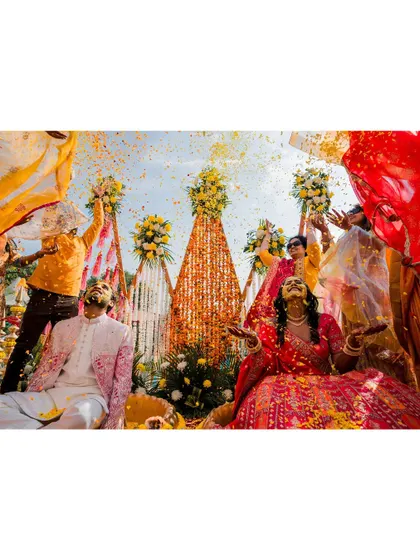 The vibrant energy of a Haldi ceremony is infectious. This shot captures the couple surrounded by friends, immersed in a storm of flower petals and laughter, a perfect kick-off to the wedding festivities.