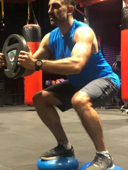 This client is performing a goblet squat on balance pods, a challenging variation that enhances core strength and stability.