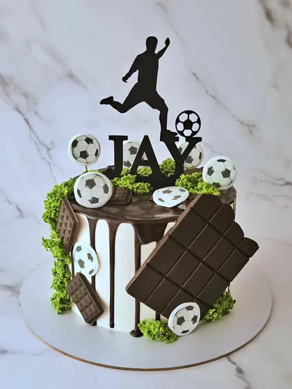 Soccer! A vanilla cake with caramel and roasted almonds, decorated with a chocolate drip, edible moss, and a soccer player silhouette.
