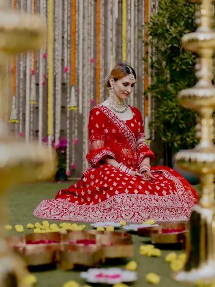 A portrait of a bride in her radiant red lehenga, seated gracefully amidst the Haldi ceremony decor.