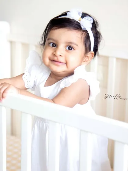 Snuggled up and safe in her crib. A simple, classic portrait in a white dress is a timeless way to capture your baby's sweetness.