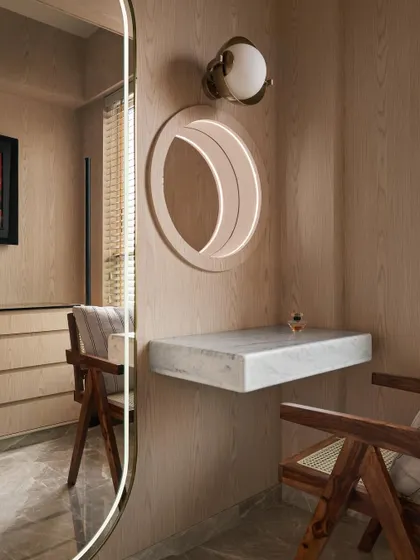 The dresser area in the master bedroom features a floating Carrara marble vanity, a side-lit mirror, and a classic Pierre Jeanneret chair. It’s a light, elegant space designed for daily routines.
