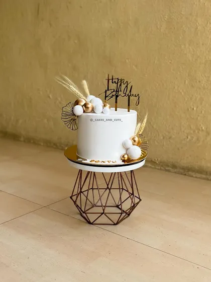 A customized white and gold beauty. This cake uses dried botanicals and gold spheres for a contemporary, bohemian look.