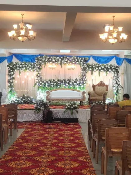 A full view of a convention hall decorated for a Half Saree ceremony, showing the main stage, aisle, and guest seating.