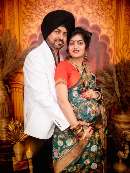 A classic portrait of the couple from their traditional maternity photoshoot. Their coordinated outfits and the warm, candle-lit setting add to the celebratory mood.
