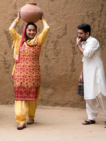 A playful and themed pre-wedding shoot with a rustic, village-like setting. This kind of creative concept makes for truly unique and memorable couple photos.