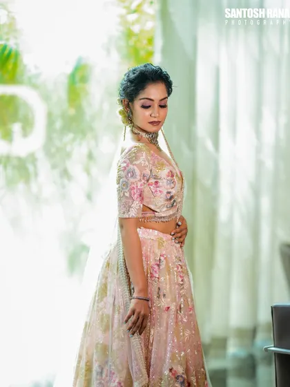 A side profile against a brightly lit window creates a soft, ethereal glow, emphasizing the silhouette of the floral lehenga.