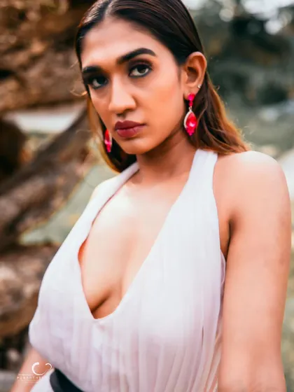 A captivating close-up that highlights her strong features and the bold pink earrings. Her gaze is intense and full of story.