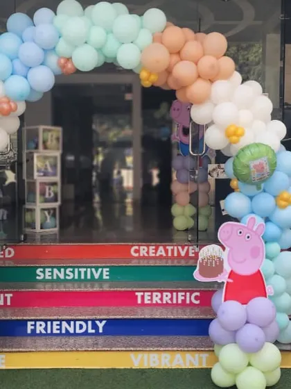 The entrance to our venue decorated for a Peppa Pig party. A character cutout and a pastel balloon arch welcome the little guests.