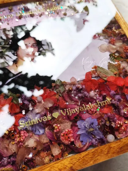 A close-up on the custom names and details within the anniversary frame, surrounded by a garden of preserved flowers.