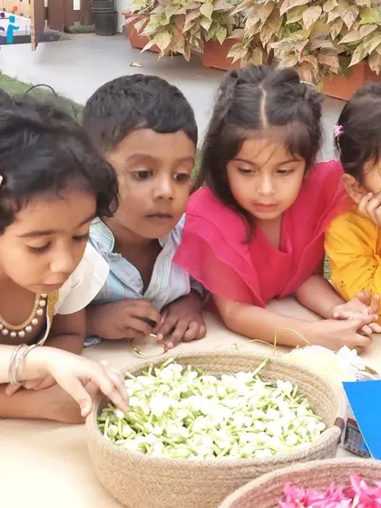 Children examine fragrant flowers before using them to create beautiful bookmarks. This sensory activity connects them with nature and the spirit of Vasant Panchami.