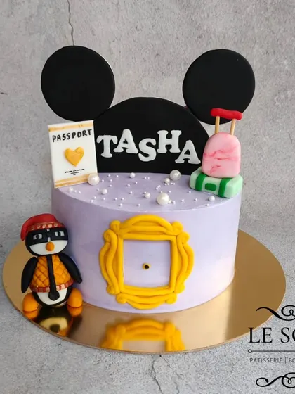 This cake combines a client's favorite things: Friends, Mickey Mouse, and travel. The 1 kg cake features the iconic yellow frame, Huggsy the penguin, and other personalized fondant details.
