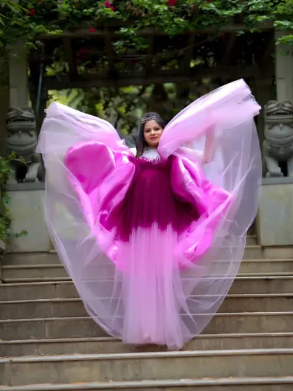 A dramatic maternity photo on a grand staircase, with the flowing fabric of the gown creating an angelic, wing-like effect.
