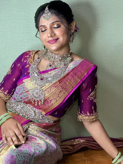 A full-length seated pose, showing the beautiful flow of the saree and the intricate details of the entire ensemble.