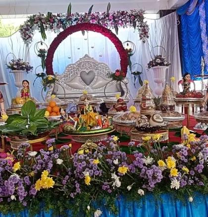 A beautiful stage setup for an engagement or wedding, with a floral arch and a heart-themed love seat. My decorated gift platters in the foreground complete the romantic and festive theme.