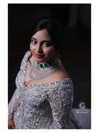 A close up of Harini's modern bridal makeup. The focus is on luminous skin and beautifully defined eyes, paired with a statement diamond and emerald necklace.