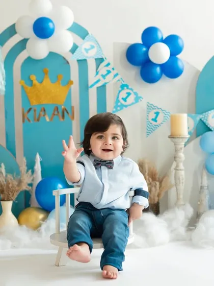A royal welcome for the little prince turning one. This blue and gold themed birthday setup features a crown, personalized banner, and a happy wave from the birthday boy.