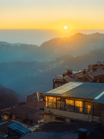 A stunning sunset over the hills of Shimla. The warm, golden light bathes the entire landscape, creating a peaceful and breathtaking view.