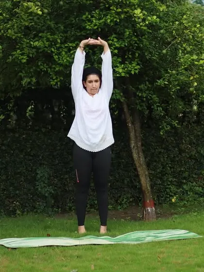 Leading the class in a standing overhead stretch to lengthen the spine and open the shoulders. Practicing under the open sky adds a special sense of freedom.