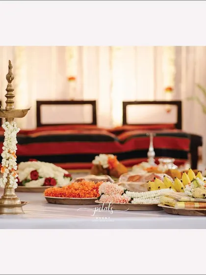 A traditional brass lamp is adorned with flowers, surrounded by offerings of fruits and garlands. These details are essential for creating a sacred and authentic ritual space.