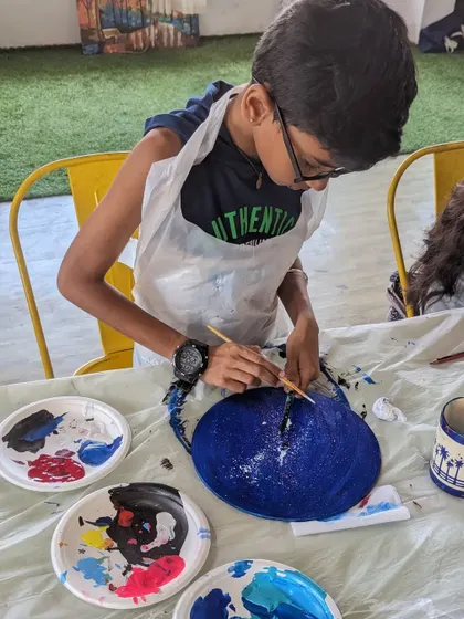 Even our youngest artists can get in on the fun! Here, a young participant is focused on painting the base for his galaxy-themed resin piece before the pouring begins.