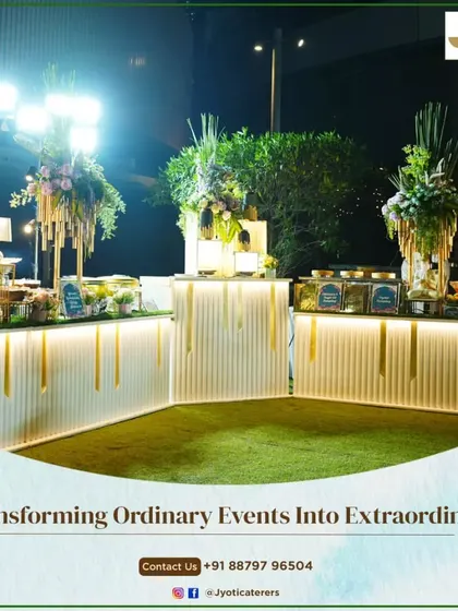 A stunning nighttime setup featuring curved, illuminated white counters on a lush green turf, topped with tall, dramatic floral arrangements.