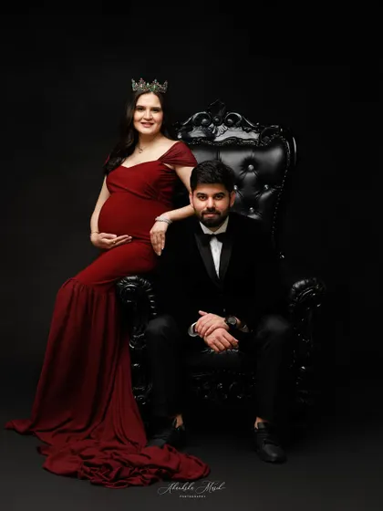 A royal-themed maternity portrait. The elegant throne and formal wear create a stunning, artistic image that celebrates the couple's journey.