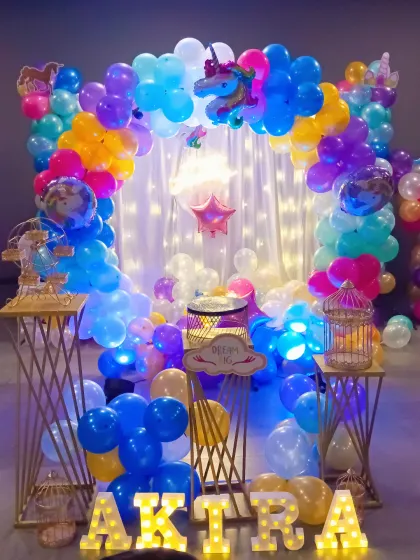 A closer view of the unicorn birthday setup, showing the mix of pastel and bright balloons. Details like the light-up name, decorative birdcages, and a central cake stand complete this dreamy party scene.