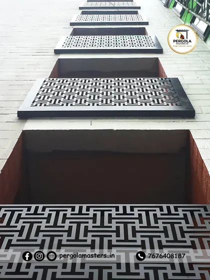 These laser-cut metal panels with a bold geometric pattern are used as window coverings or decorative facade elements. The view from below shows the repeating design, which adds a strong graphic quality to the building's exterior.