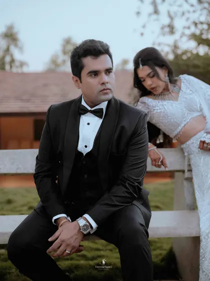 A candid shot of the couple at their outdoor reception, with the groom seated and the bride leaning in.