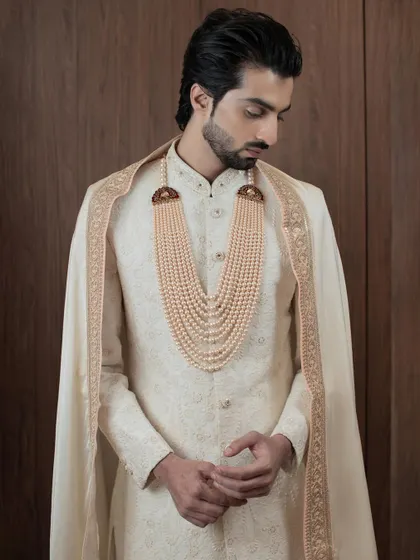 This portrait captures the regal essence of our groom's collection. The ivory sherwani, paired with a cape and pearl mala, is a perfect example of how I blend heritage with high fashion.