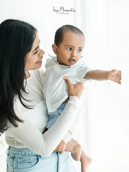 A mother holds her baby boy up to the light. This simple composition creates a beautiful silhouette effect and highlights the baby's curious gaze as he looks out the window.