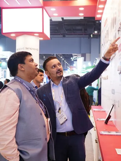 A moment of discovery as an exhibitor points out key details of a lighting solution to an engaged attendee.