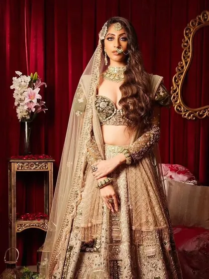 A modern bridal look with a touch of tradition. The hair is styled in long, flowing waves, and the makeup is glamorous with a focus on the eyes.