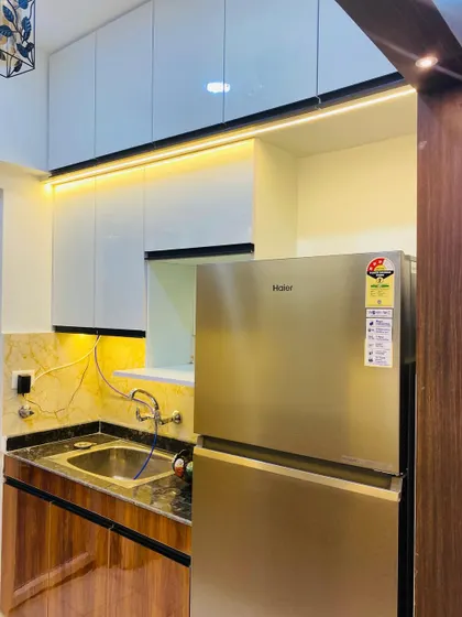 A compact kitchen space next to the main entrance. We used dual-tone laminates and profile lighting to make it look stylish.