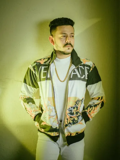 A casual yet stylish portrait from a men's fashion shoot. The use of a colored gel creates a modern, urban vibe, highlighting the designer jacket and the subject's relaxed confidence.